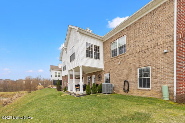 rear view of house featuring brick siding, a yard, and central air condition unit