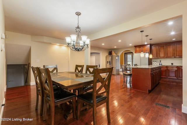 dining room with arched walkways, dark wood finished floors, an inviting chandelier, and recessed lighting