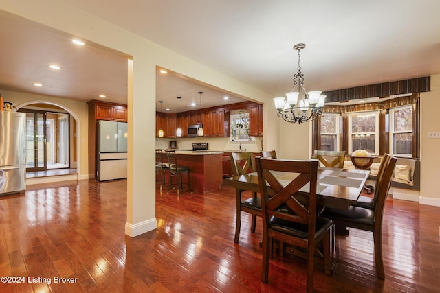 dining area with arched walkways, dark wood finished floors, recessed lighting, an inviting chandelier, and baseboards