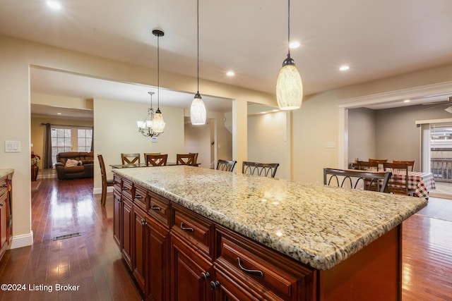 kitchen featuring light stone counters, dark wood finished floors, decorative light fixtures, and recessed lighting