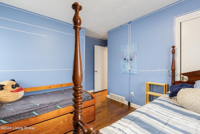 bedroom with wood finished floors, visible vents, and baseboards