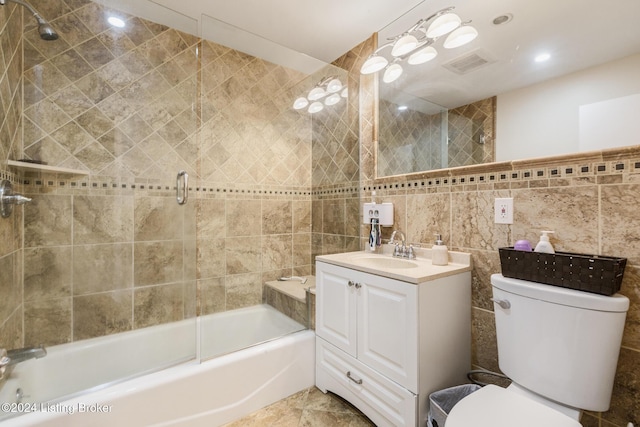 bathroom with visible vents, bath / shower combo with glass door, toilet, vanity, and tile walls