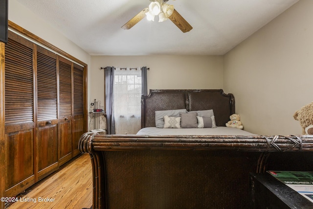 bedroom with light wood-style flooring, ceiling fan, and a closet