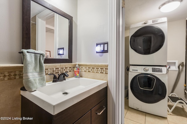 clothes washing area with stacked washer / drying machine, laundry area, a sink, and light tile patterned floors