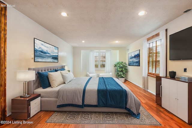 bedroom featuring a textured ceiling, light wood-style flooring, and recessed lighting