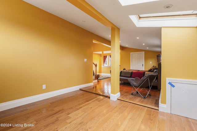 interior space featuring stairway, lofted ceiling with skylight, light wood-style flooring, and baseboards