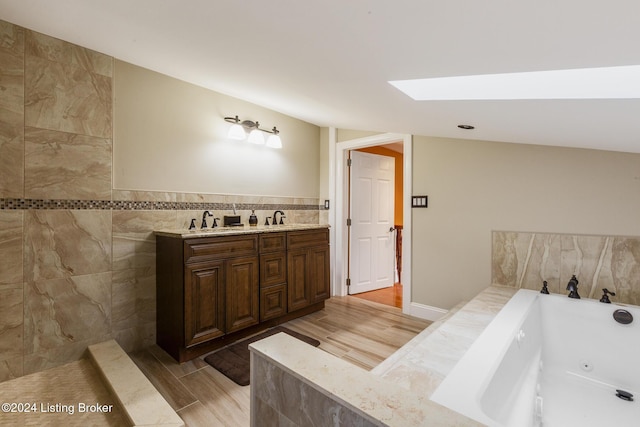 full bathroom featuring a sink, tile walls, a whirlpool tub, and wood finished floors