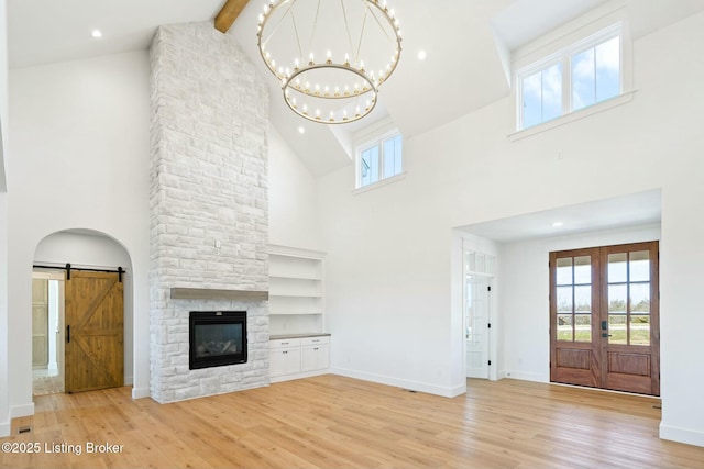 unfurnished living room with a barn door, plenty of natural light, and wood finished floors