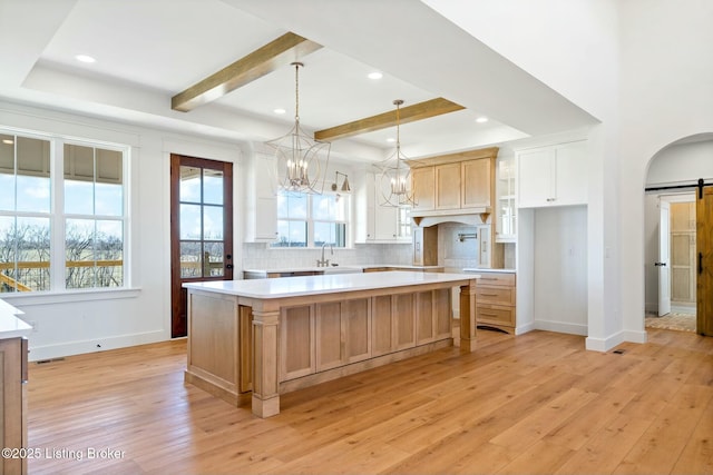 kitchen featuring light wood finished floors, a large island, a sink, a barn door, and light countertops