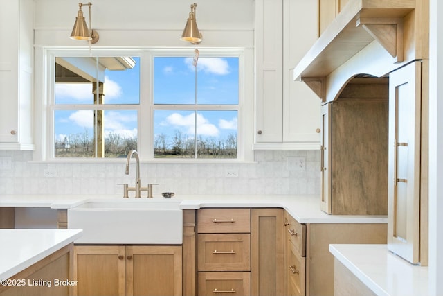 kitchen featuring decorative light fixtures, decorative backsplash, light countertops, and a sink