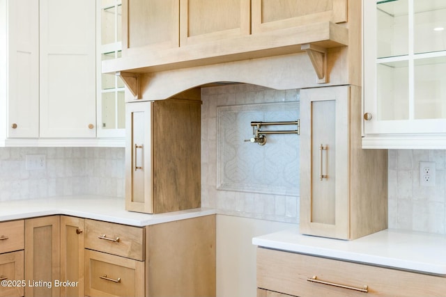 kitchen with glass insert cabinets, tasteful backsplash, white cabinets, and light countertops