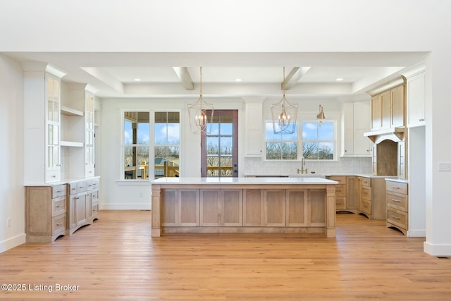 kitchen with light wood finished floors, a center island, backsplash, and a chandelier