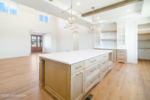 kitchen with open shelves, visible vents, light wood-style floors, and an inviting chandelier