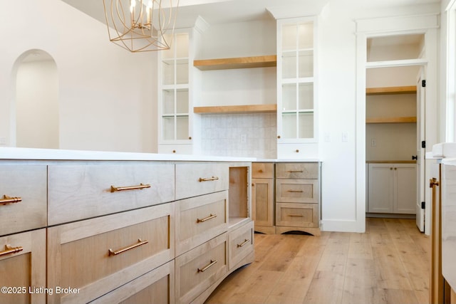 interior space with an inviting chandelier, light wood-style flooring, and arched walkways