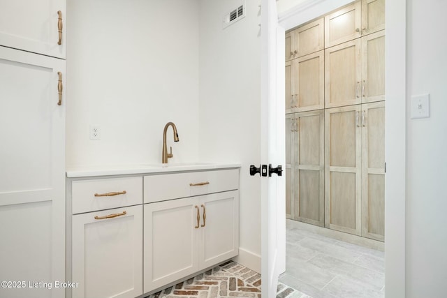 bathroom featuring visible vents, brick floor, and a sink