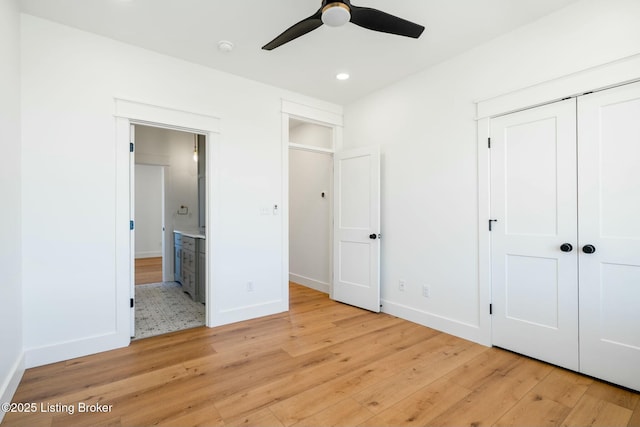 unfurnished bedroom with ensuite bath, light wood-style floors, baseboards, and a closet