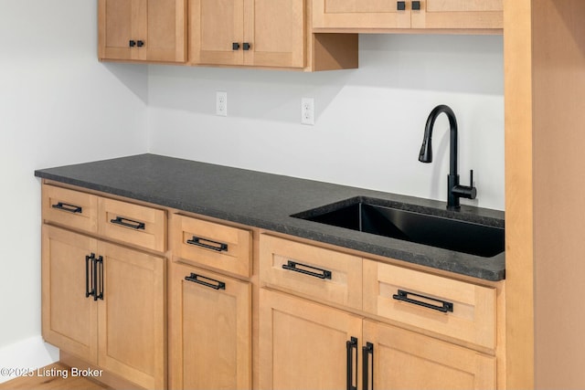 kitchen featuring a sink, dark countertops, and light brown cabinets