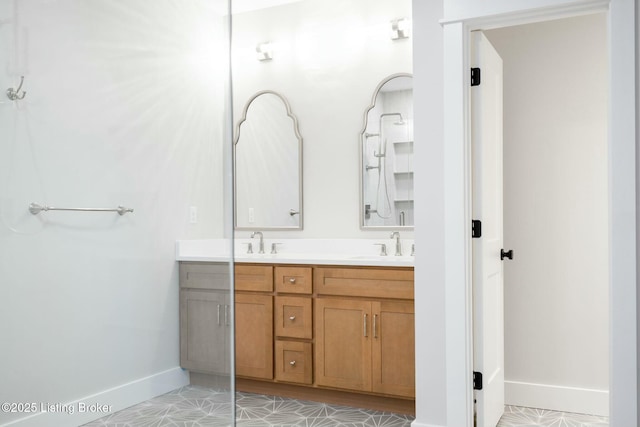 full bathroom featuring double vanity, baseboards, and a sink