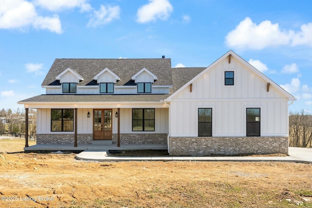 modern farmhouse with french doors, board and batten siding, a shingled roof, and brick siding