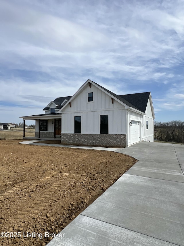 modern inspired farmhouse with board and batten siding, brick siding, driveway, and a garage