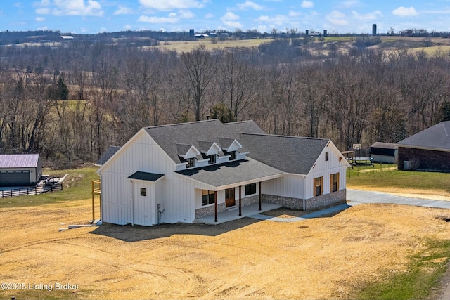 view of front of property with board and batten siding, a front lawn, and roof with shingles