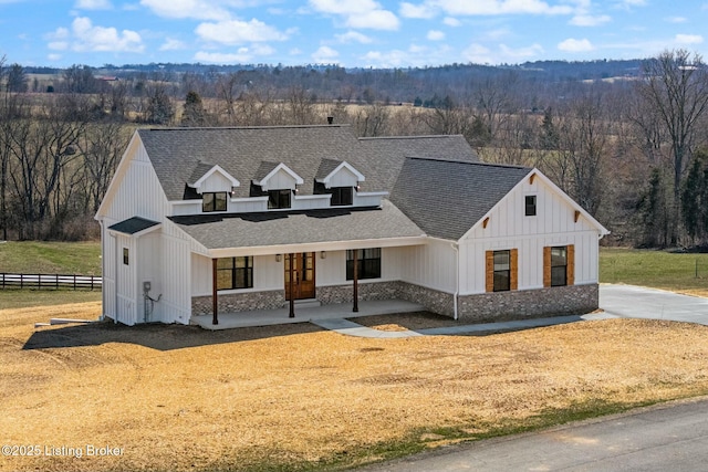 modern inspired farmhouse with covered porch, fence, board and batten siding, and roof with shingles