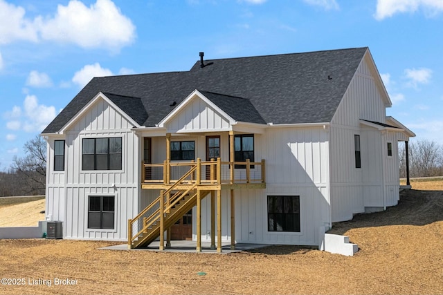 back of property with board and batten siding, a shingled roof, stairway, central AC unit, and a patio area