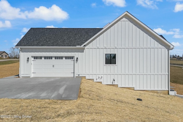 view of side of property featuring a garage, board and batten siding, and roof with shingles