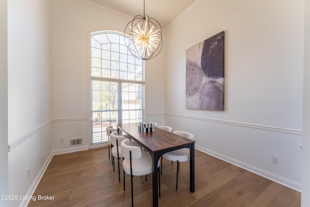 dining area featuring a notable chandelier, wood finished floors, visible vents, baseboards, and ornamental molding