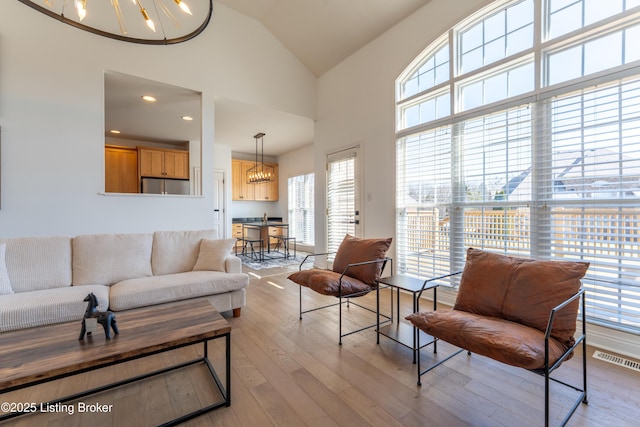 living room with recessed lighting, visible vents, light wood-style flooring, an inviting chandelier, and high vaulted ceiling