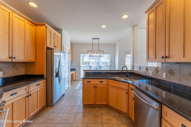 kitchen featuring light tile patterned flooring, stainless steel appliances, a sink, tasteful backsplash, and dark stone countertops