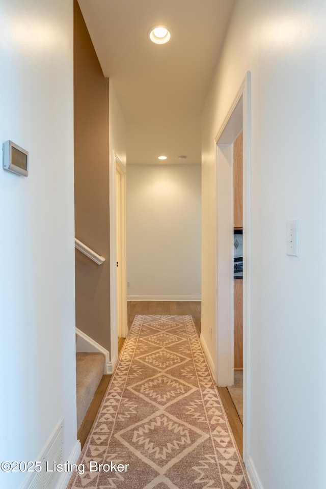 hallway featuring stairs, baseboards, and recessed lighting