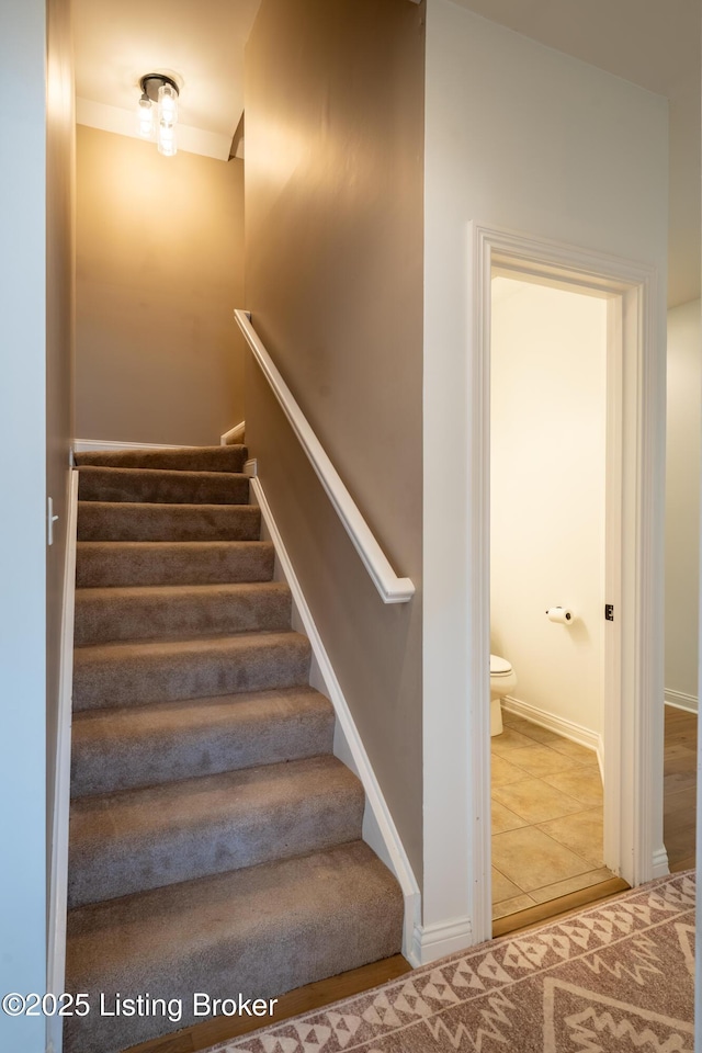 stairway with baseboards and tile patterned floors