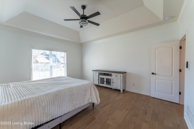 bedroom with a raised ceiling, crown molding, baseboards, and wood finished floors