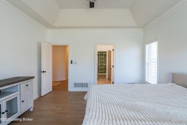 bedroom featuring a tray ceiling, wood finished floors, visible vents, and crown molding