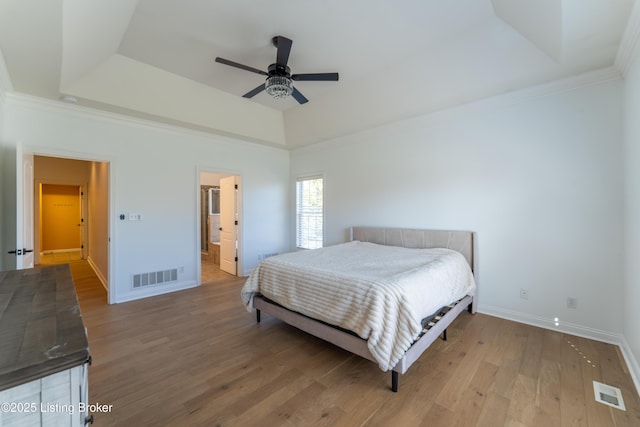 bedroom with a raised ceiling, visible vents, and wood finished floors