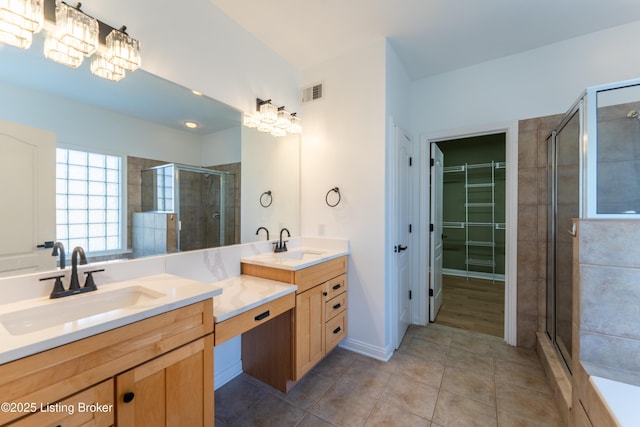 bathroom featuring tile patterned flooring, vanity, visible vents, a stall shower, and a walk in closet