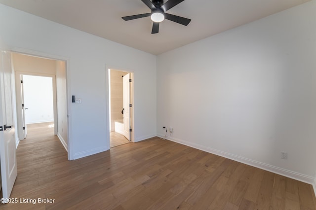 unfurnished bedroom featuring connected bathroom, baseboards, and wood finished floors