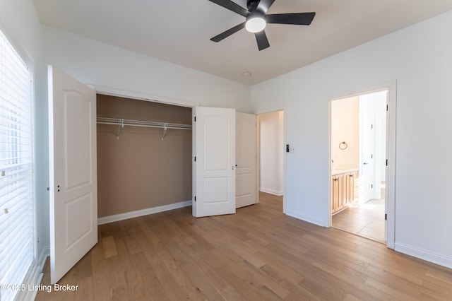 unfurnished bedroom featuring ceiling fan, ensuite bathroom, baseboards, light wood-style floors, and a closet