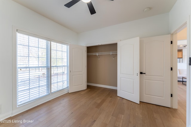 unfurnished bedroom featuring baseboards, a closet, a ceiling fan, and light wood-style floors