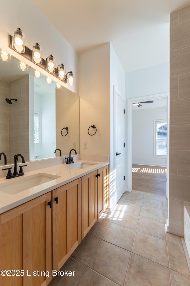 bathroom featuring a wealth of natural light, tile patterned flooring, a sink, and tiled shower