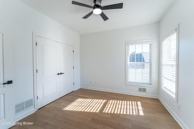 unfurnished bedroom with visible vents, baseboards, and wood finished floors