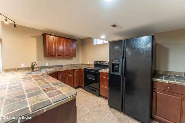 kitchen featuring tile counters, visible vents, a peninsula, black appliances, and a sink