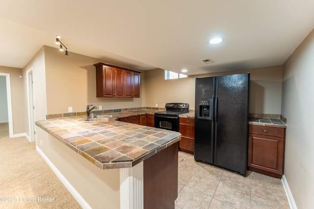 kitchen with tile countertops, a breakfast bar area, a peninsula, black appliances, and a sink