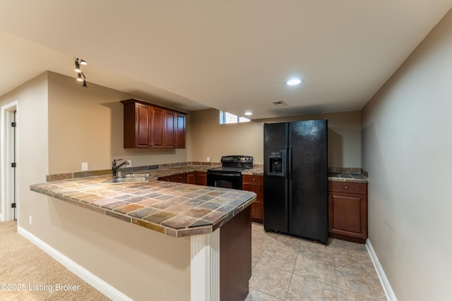 kitchen with baseboards, tile countertops, a peninsula, black appliances, and a sink