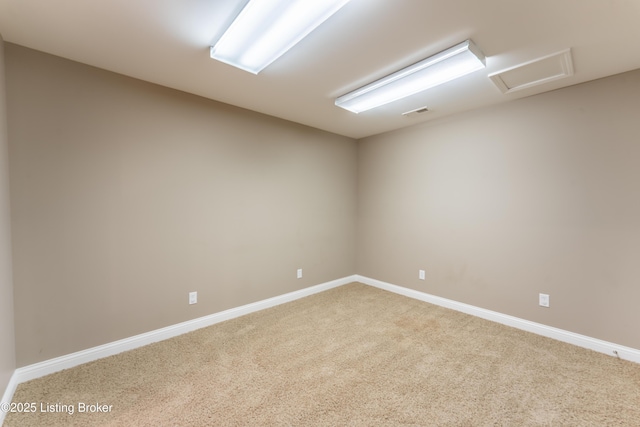 unfurnished room with visible vents, carpet floors, attic access, and baseboards