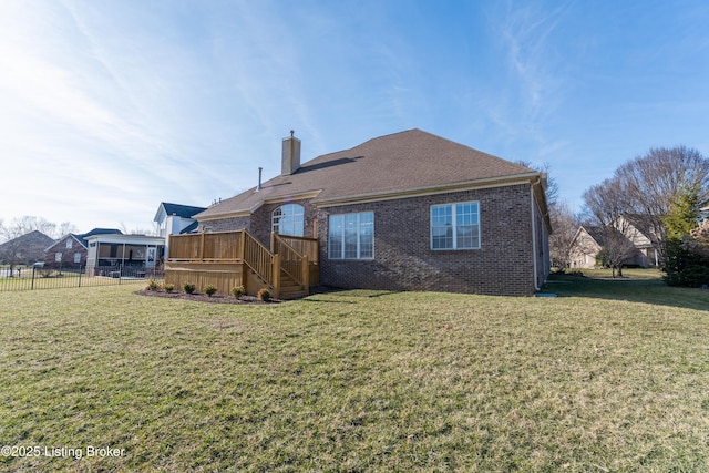 rear view of property with brick siding, a yard, a chimney, and fence