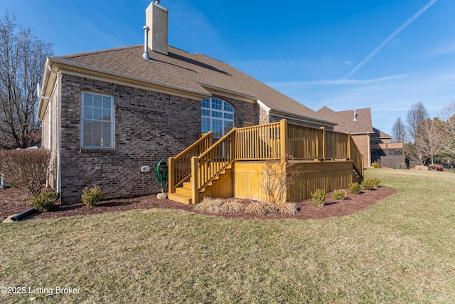 back of property featuring a deck, brick siding, stairs, a lawn, and a chimney