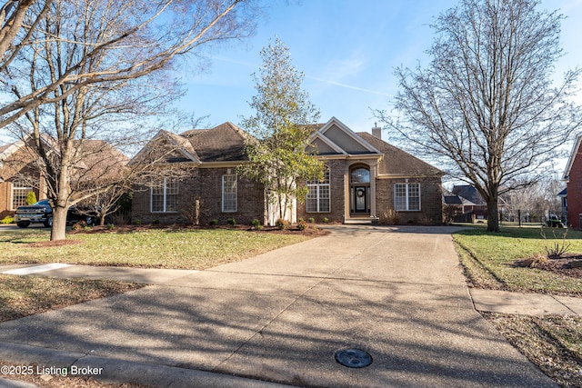 view of front facade featuring brick siding, driveway, a chimney, and a front lawn