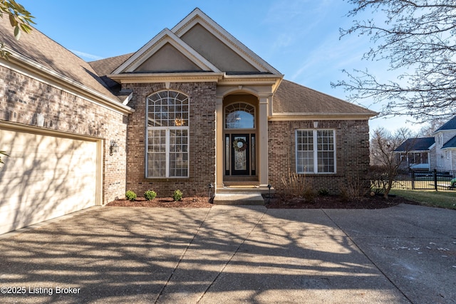 traditional-style house with an attached garage, driveway, fence, and brick siding